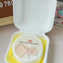 Round cake with a love message inside a white takeaway box, ideal for romantic celebrations.